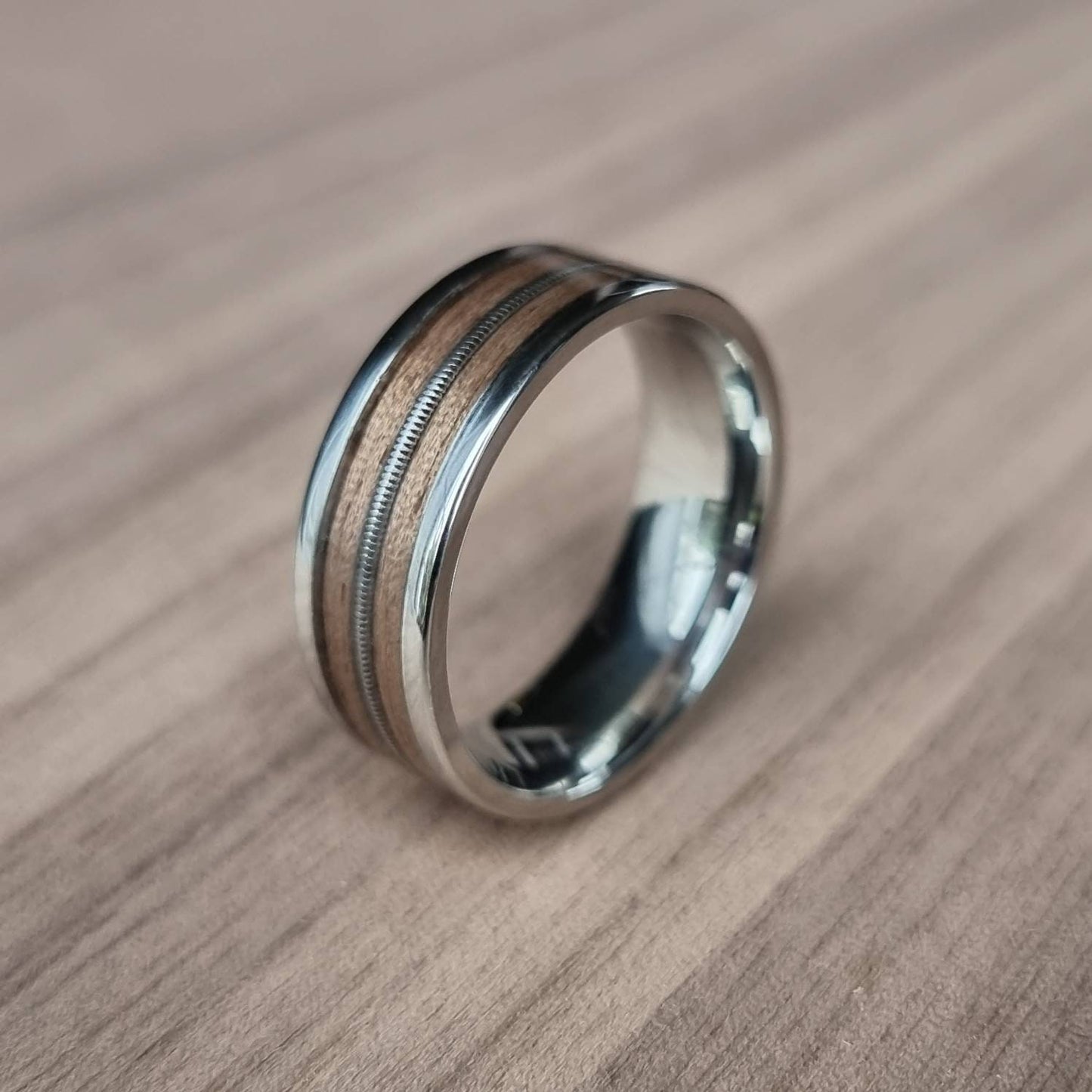 Stainless steel and walnut ring with guitar string inlay