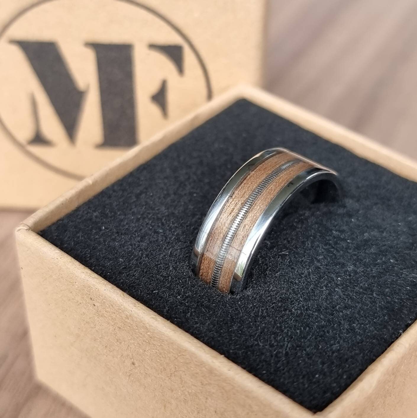 Stainless steel and walnut ring with guitar string inlay